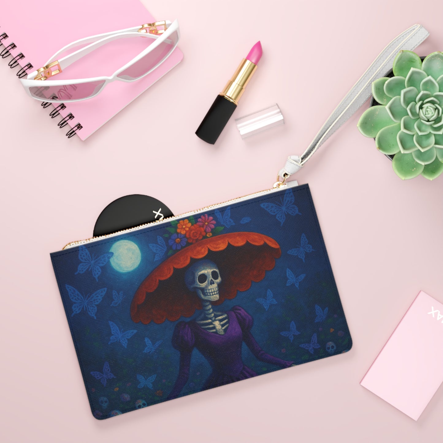 Pouch with skeleton design on a pink surface with makeup items